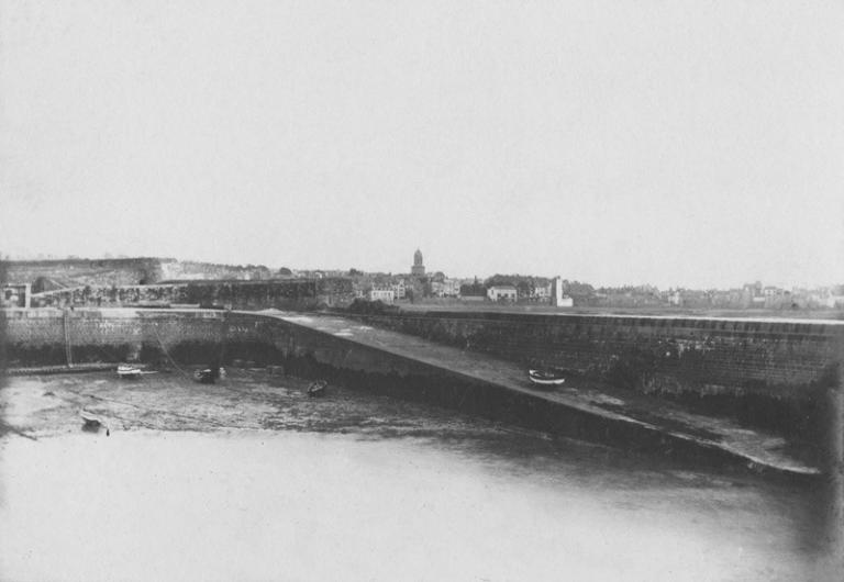 Vue générale depuis le nord. De gauche à droite, on distingue le fort du Naye et l'avant-port avec digue et cale. La marée est basse. En arrière-plan, la ville de Saint-Servan