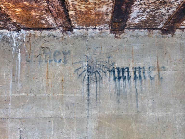 Vue de détail de la peinture murale du magasin à munitions figurant une araignée sur sa toile. Elle est entourée de l'inscription en lettre gothique  : Eïner / immer